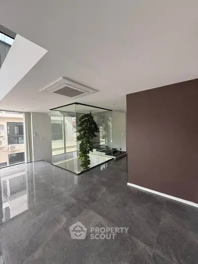 Modern interior with sleek flooring and glass enclosure, abundant natural light.