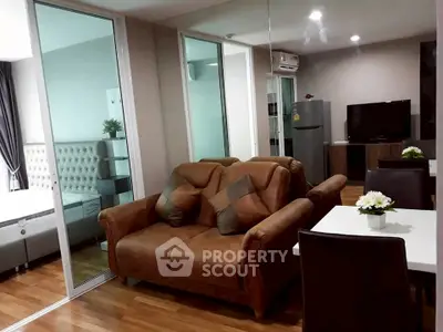 Modern living room with brown leather sofa, dining area, and view into bedroom