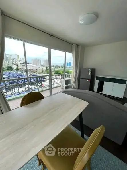 Modern living room with large windows and city view, featuring stylish furniture and natural light.