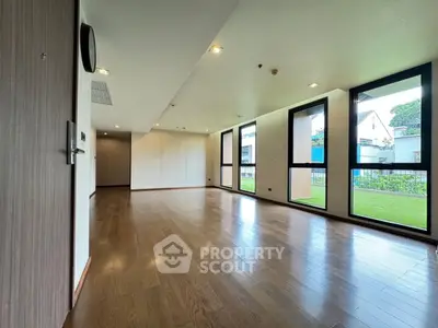 Spacious empty living room with large windows and wooden flooring