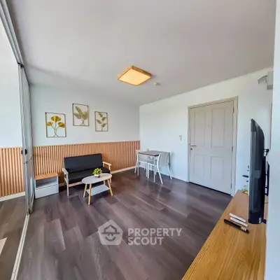 Modern living room with stylish decor and wooden flooring, featuring a cozy seating area and a TV unit.