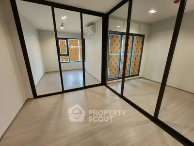 Spacious room with mirrored closet doors and large windows in modern apartment