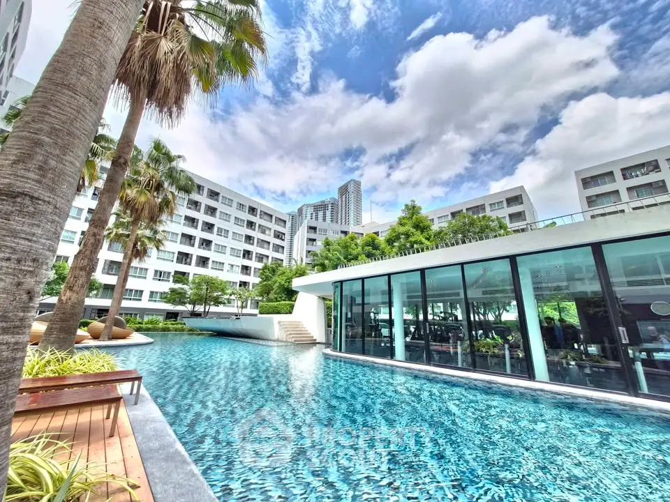 Luxurious condominium with stunning pool and modern architecture under a vibrant sky.