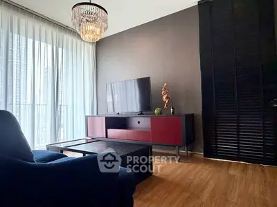 Modern living room with elegant chandelier and sleek furniture, featuring a large window with sheer curtains.