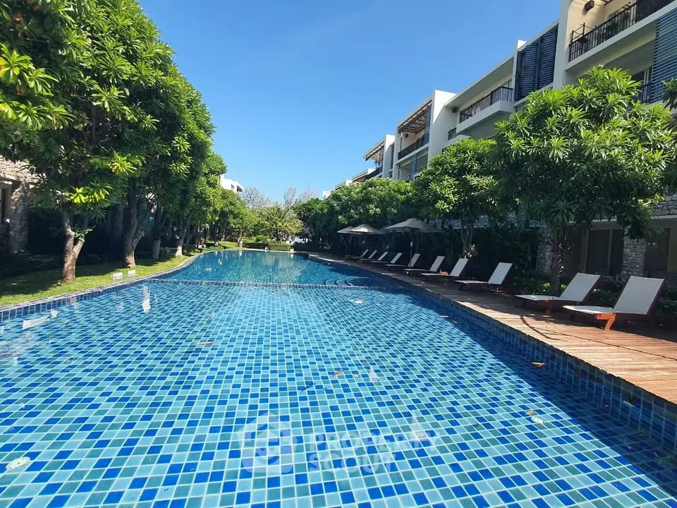 Luxurious outdoor pool area with sun loungers and lush greenery at a modern residential complex.