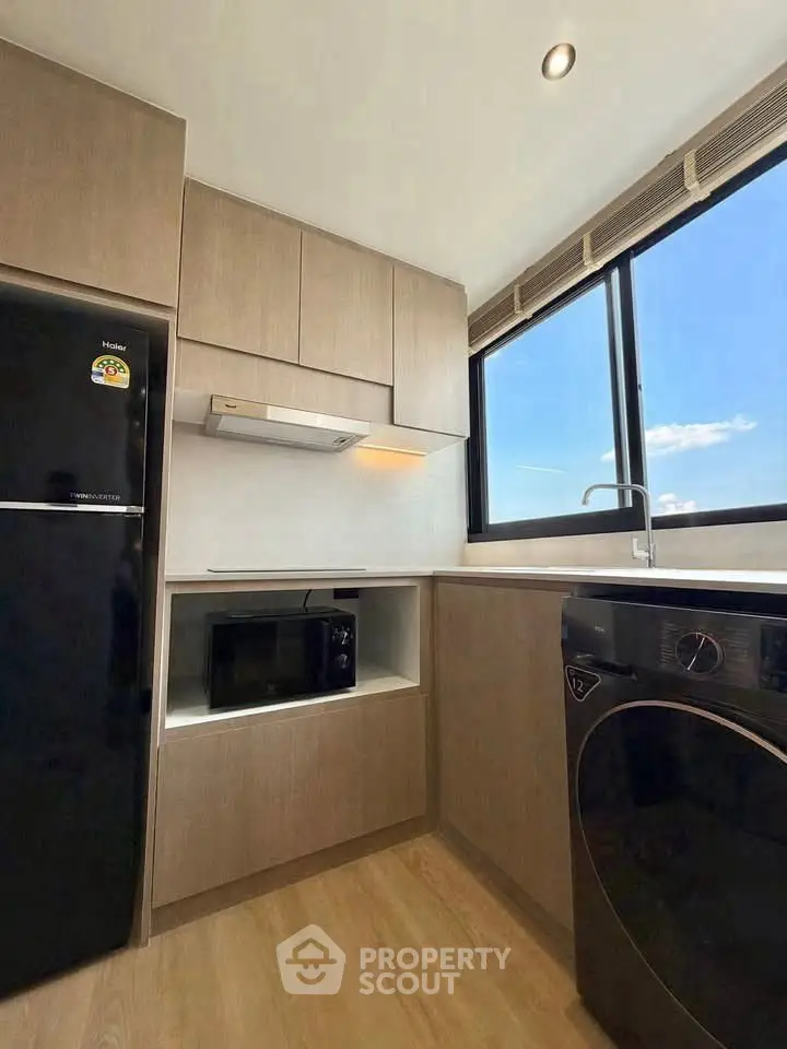 Modern kitchen with sleek appliances and large window offering natural light.