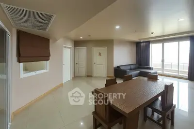 Spacious living room with modern dining set and large windows for natural light.