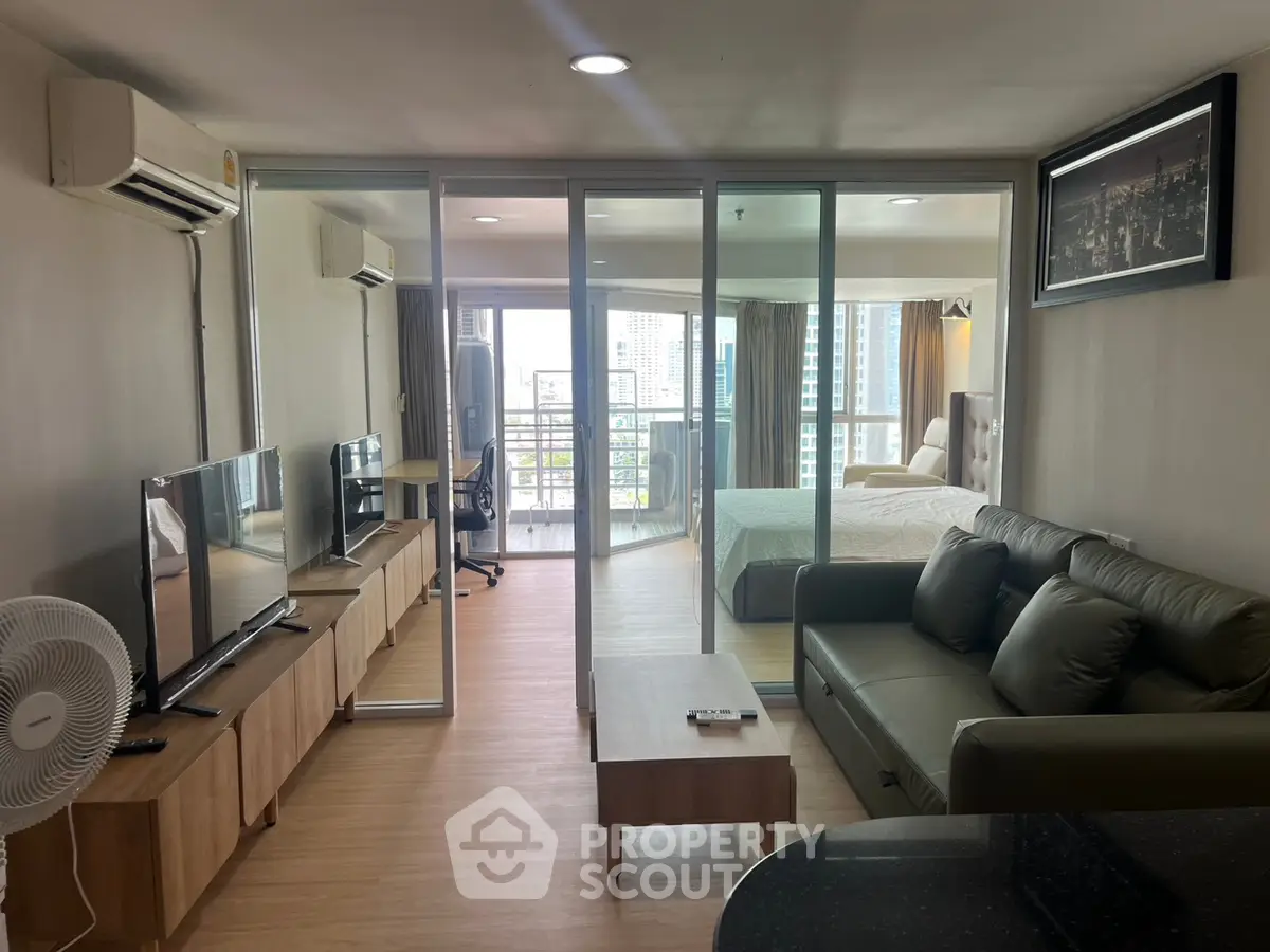Modern living room with glass partition, cozy sofa, and city view from balcony in stylish apartment.