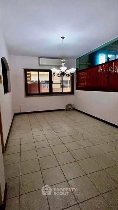 Spacious tiled room with chandelier and large windows in a modern apartment.