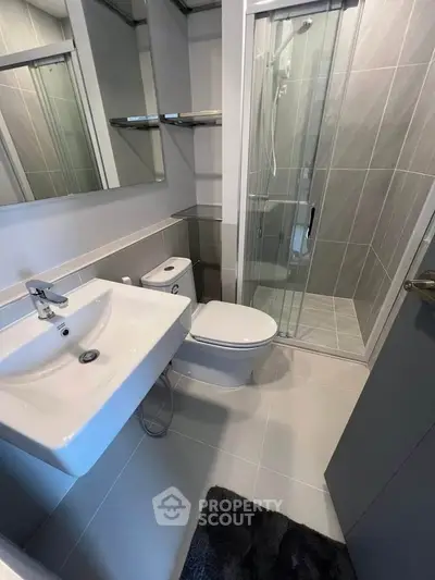 Modern bathroom with sleek fixtures and glass shower enclosure in contemporary apartment.