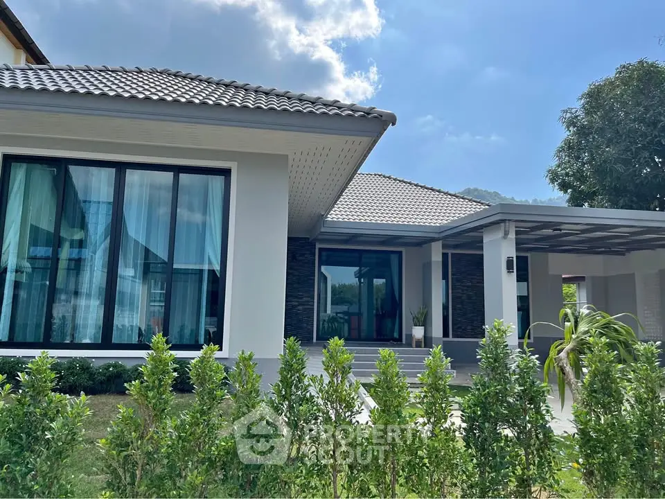 Charming modern house with lush garden and spacious driveway under clear blue sky.