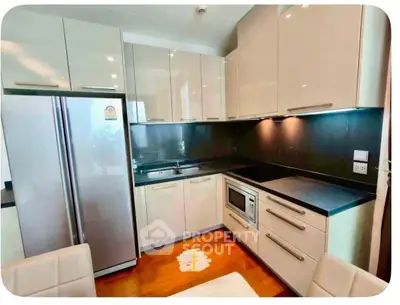 Modern kitchen with sleek cabinetry, stainless steel appliances, and elegant black countertops.