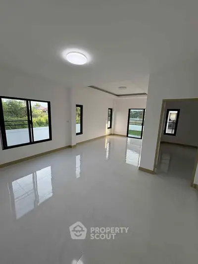Spacious empty living room with large windows and glossy tiled floor