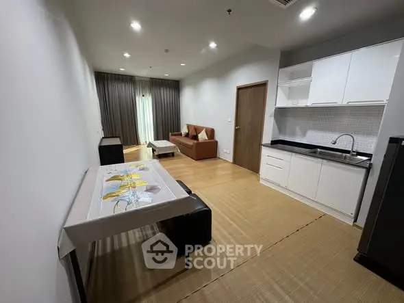 Modern open-layout living room with kitchen in a stylish apartment, featuring sleek furniture and elegant decor.