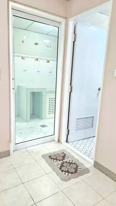 Modern bathroom entrance with tiled flooring and glass door