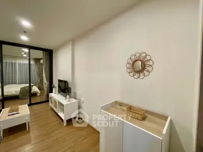 Modern living room with stylish decor and wooden flooring, featuring a cozy bedroom view.