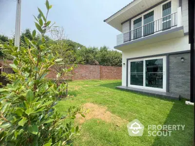 Charming two-story home with lush green garden and modern balcony