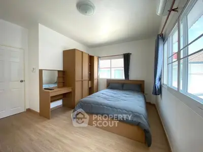 Spacious bedroom with modern furniture and large windows for natural light.