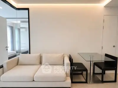 Modern living room with sleek sofa and glass dining table in a stylish apartment.