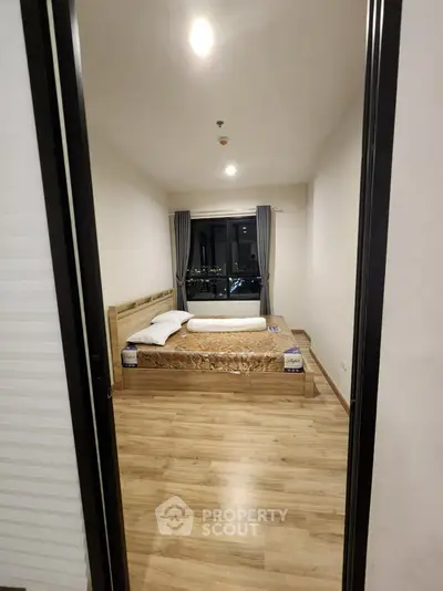 Cozy bedroom with wooden flooring and city view from window