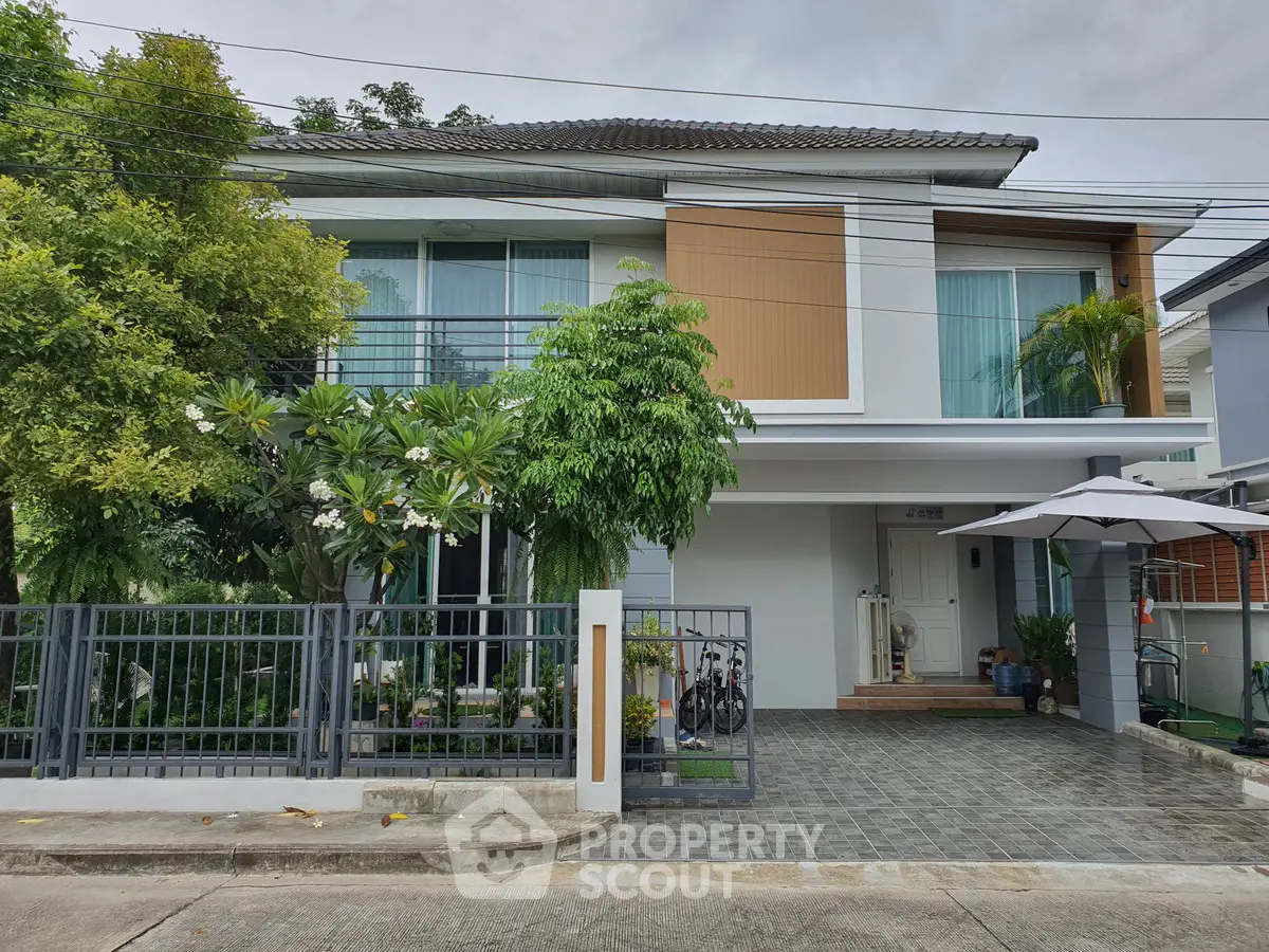 Modern two-story house with lush greenery and spacious driveway in a serene neighborhood.