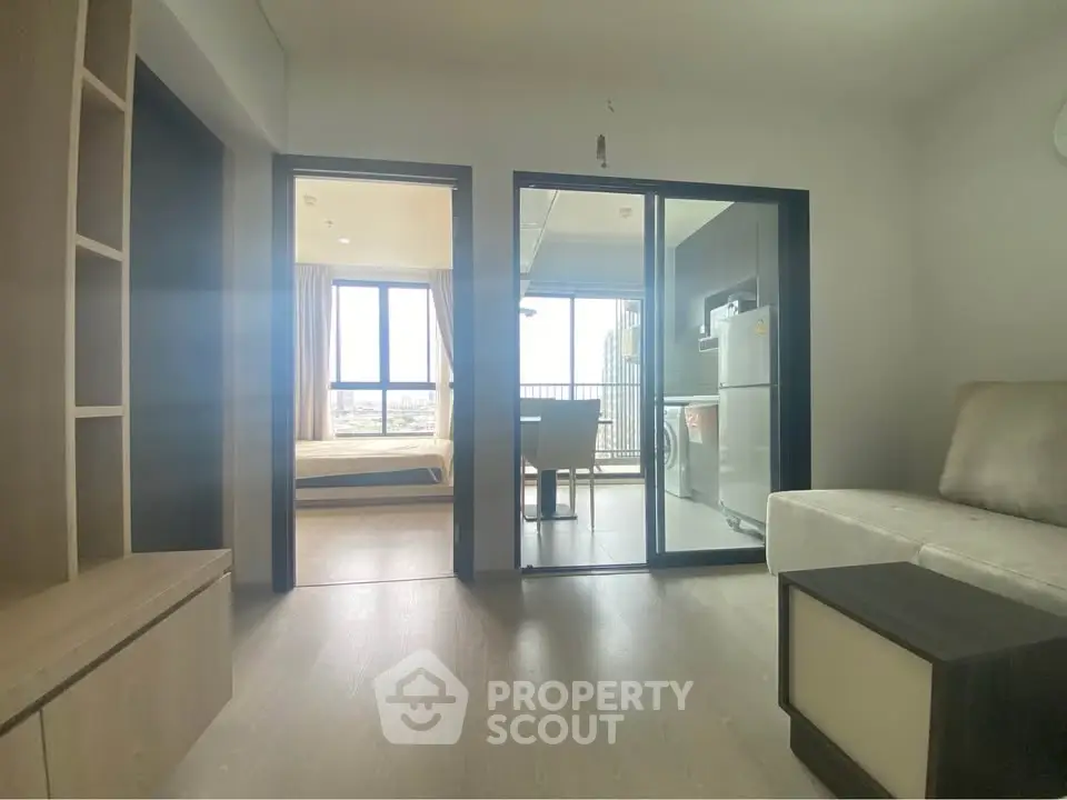 Modern apartment interior with open layout, featuring a cozy living area, kitchen, and balcony view.
