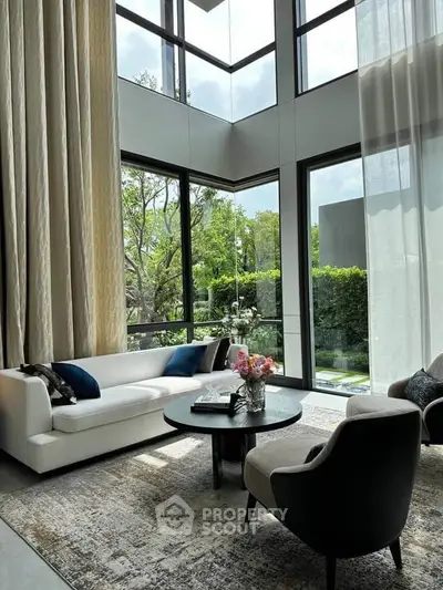 Luxurious living room with high ceilings and large windows offering a stunning garden view.