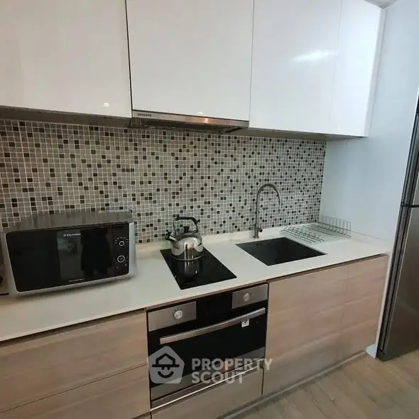 Modern kitchen with sleek cabinetry, built-in oven, and stylish backsplash.
