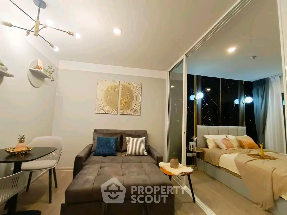 Modern living room with stylish decor and cozy bedroom separated by glass partition.