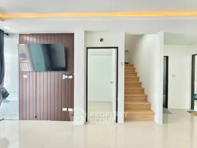 Modern interior with sleek staircase and wall-mounted TV in bright living space