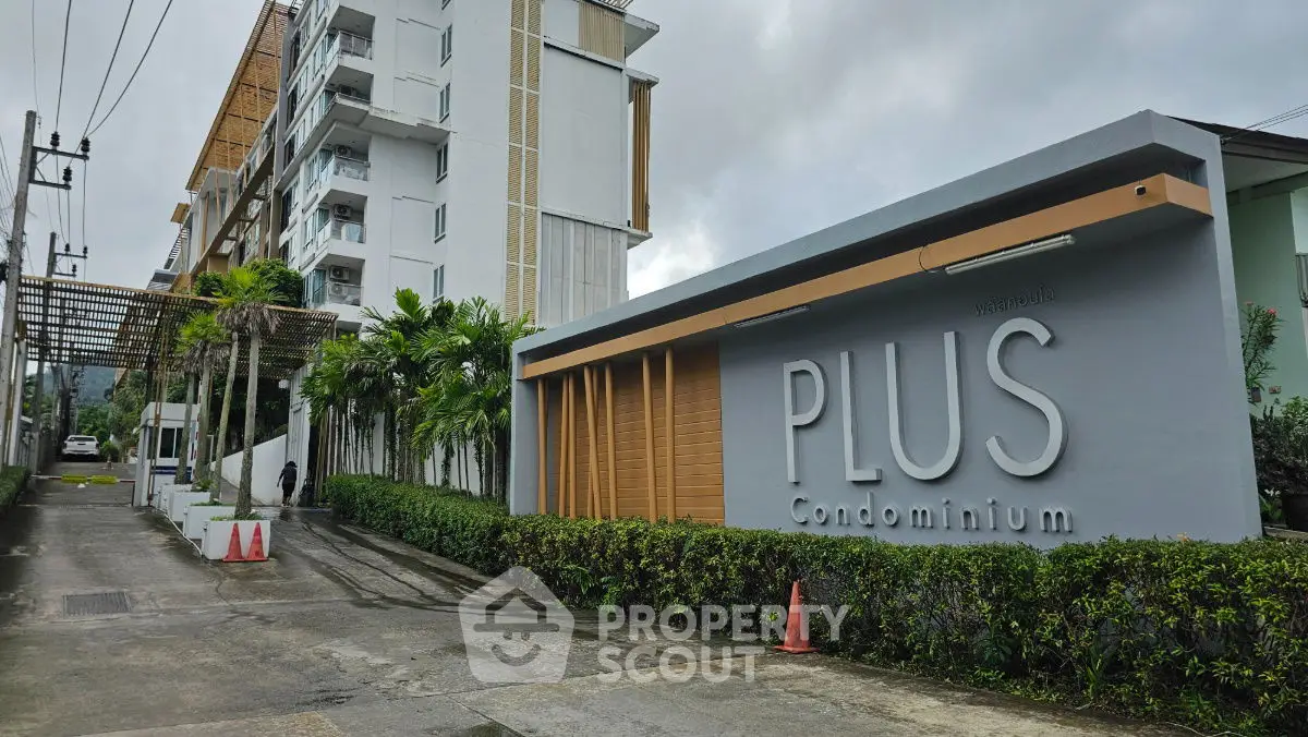 Modern condominium entrance with lush greenery and sleek architectural design.