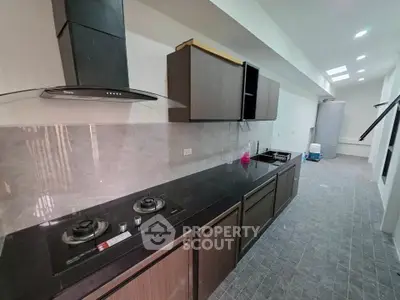 Modern kitchen with sleek black countertops and gas stove in a spacious open layout.
