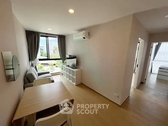 Modern living room with natural light, wooden flooring, and stylish furniture in a cozy apartment.