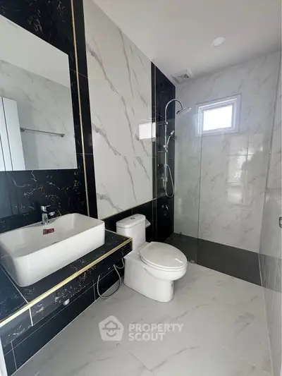 Modern bathroom with sleek black and white marble design and glass shower.