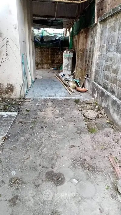 Outdoor space with paved pathway and garden hose, potential for renovation or landscaping.