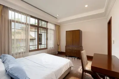 Spacious bedroom with large window and elegant wooden furniture