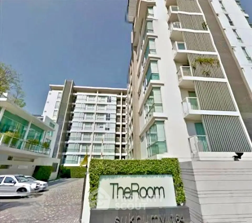 Modern condominium building exterior with lush greenery and sleek design in prime urban location.