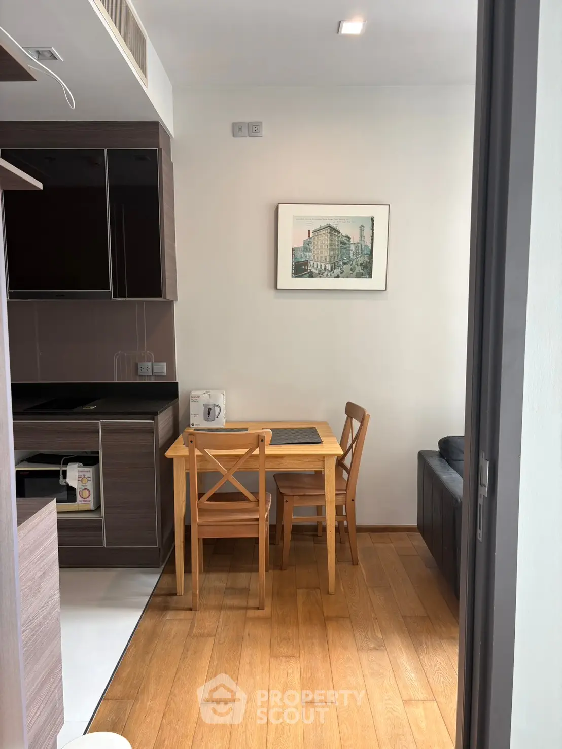 Cozy dining area with wooden flooring and modern kitchen setup in a compact apartment.