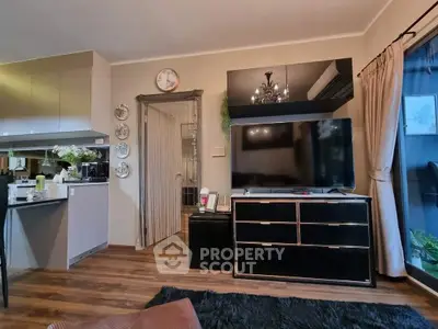 Modern living room with sleek TV setup and stylish decor, featuring open kitchen layout and elegant flooring.