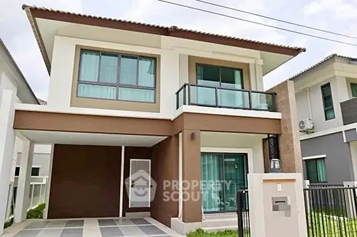 Modern two-story house with large windows and a covered carport in a suburban neighborhood.