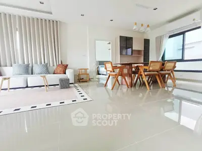 Spacious modern living room with sleek furniture and large windows in a bright apartment.