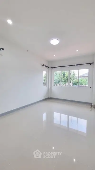 Spacious empty room with large windows and glossy tiled floor, perfect for customization.
