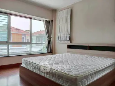 Spacious bedroom with large window offering natural light and neighborhood view.