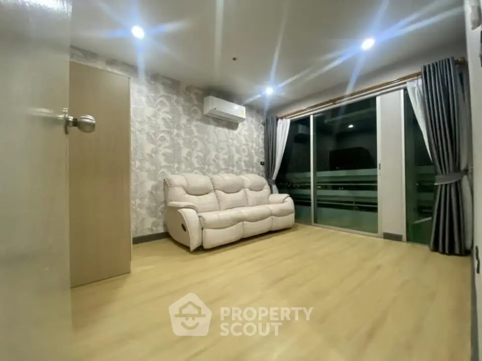 Spacious living room with modern decor and large sliding glass doors leading to balcony.