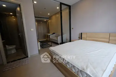 Modern bedroom with ensuite bathroom and cozy seating area in a stylish apartment.