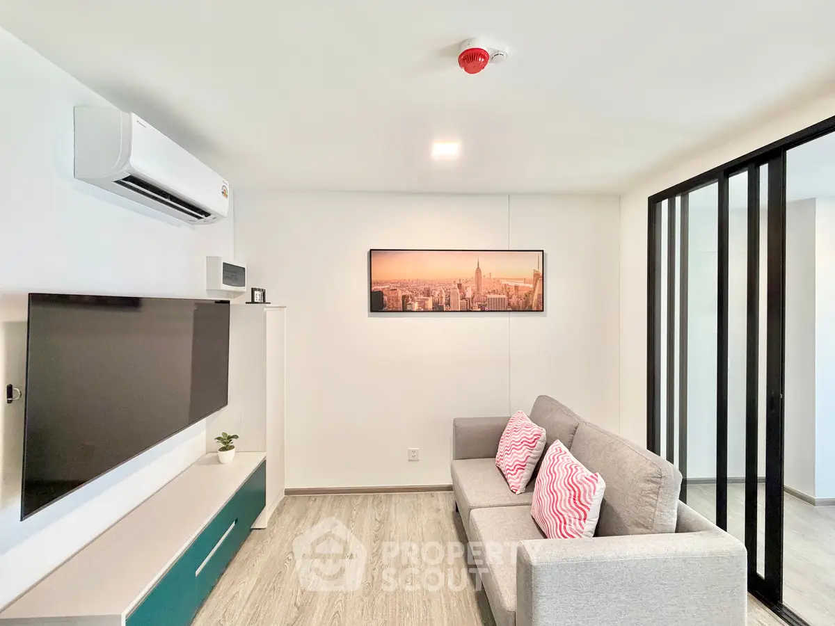 Modern living room with sleek design, featuring a wall-mounted TV, air conditioning, and stylish decor.