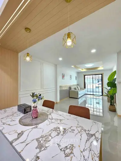 Modern open-plan living room with elegant marble dining table and stylish lighting fixtures.