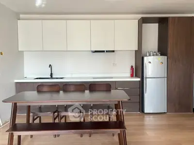 Modern kitchen with sleek cabinetry and dining area, featuring a stylish table and chairs.