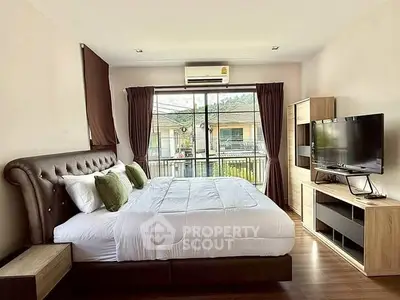 Spacious bedroom with modern decor and balcony view, perfect for relaxation.