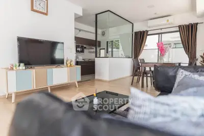Modern living room with stylish decor and open layout, featuring a large TV and dining area.